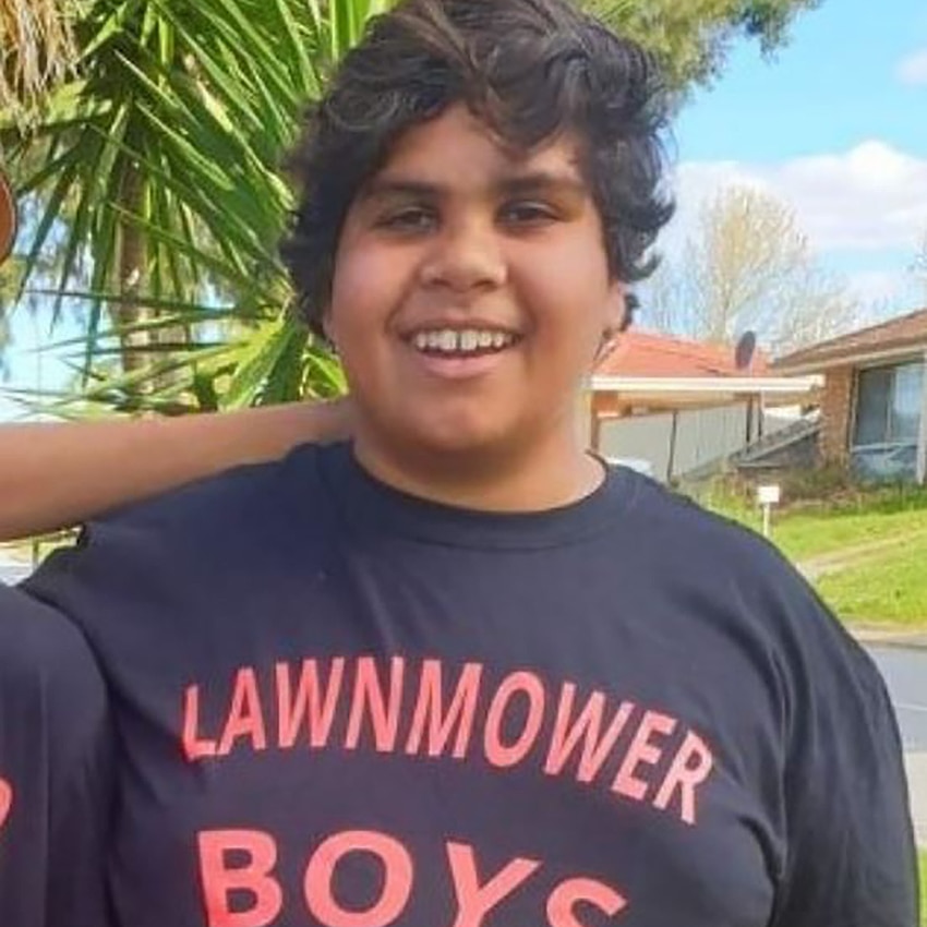 A young boy in a t-shirt that says 'lawnmower boys'