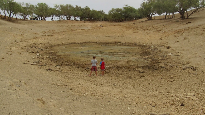 Two boys look onto a dried out dam.
