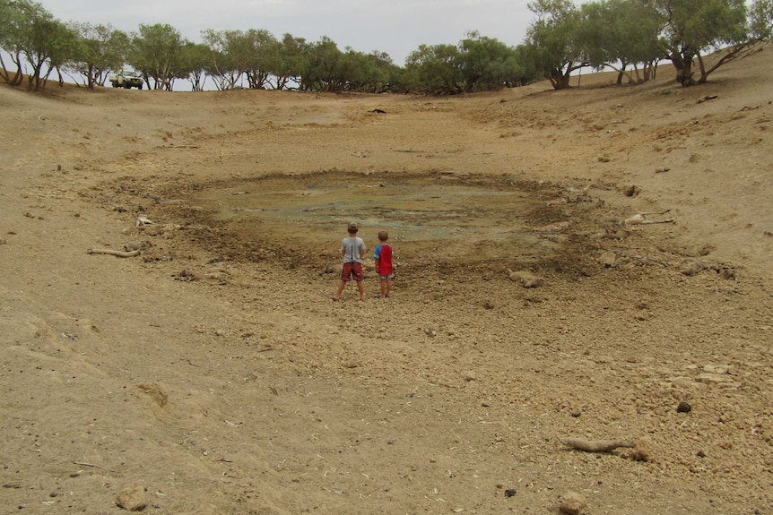 Two boys look onto a dried out dam.