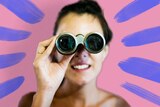 Woman looking through binoculars for story about looking through your own bias