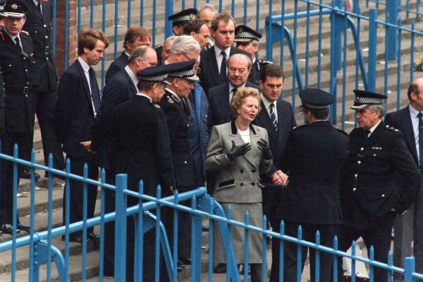 Then British prime minister Margaret Thatcher is shown the enclosure where the crowd was crushed.