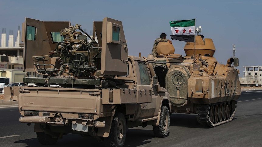 Turkish-backed Syrian opposition fighters drive in tanks along a street