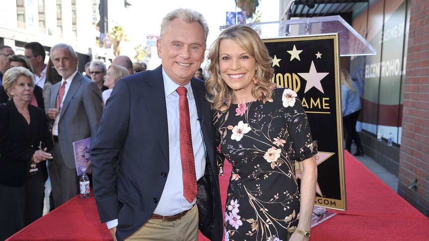 A man with greying hair and a blonde woman pose for a photo at the Hollywood Walk of Fame.
