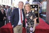 A man with greying hair and a blonde woman pose for a photo at the Hollywood Walk of Fame.