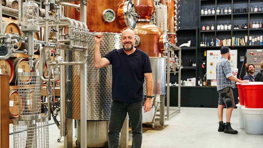 Australian Distillers Association president Stuart Gregor stands next to a still.