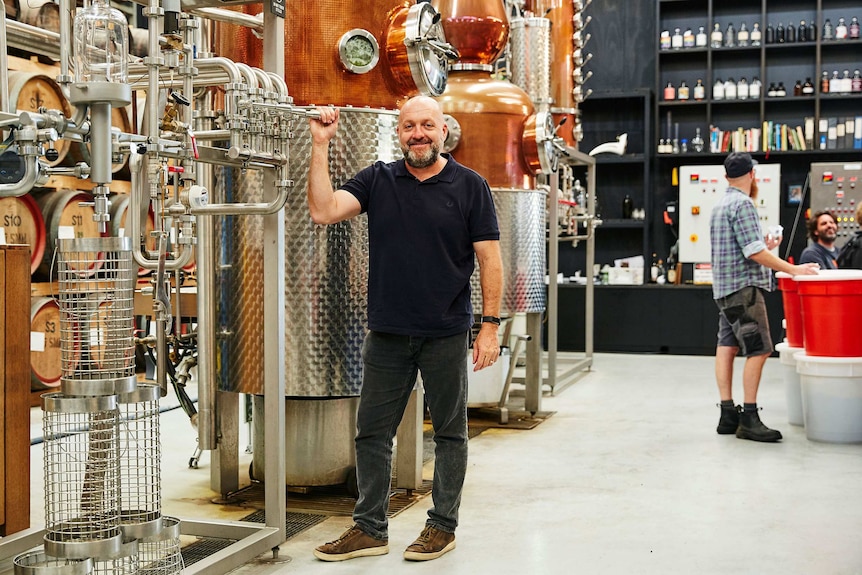 Australian Distillers Association president Stuart Gregor stands next to a still.