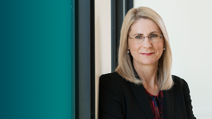 A woman with glasses looks at the camera.