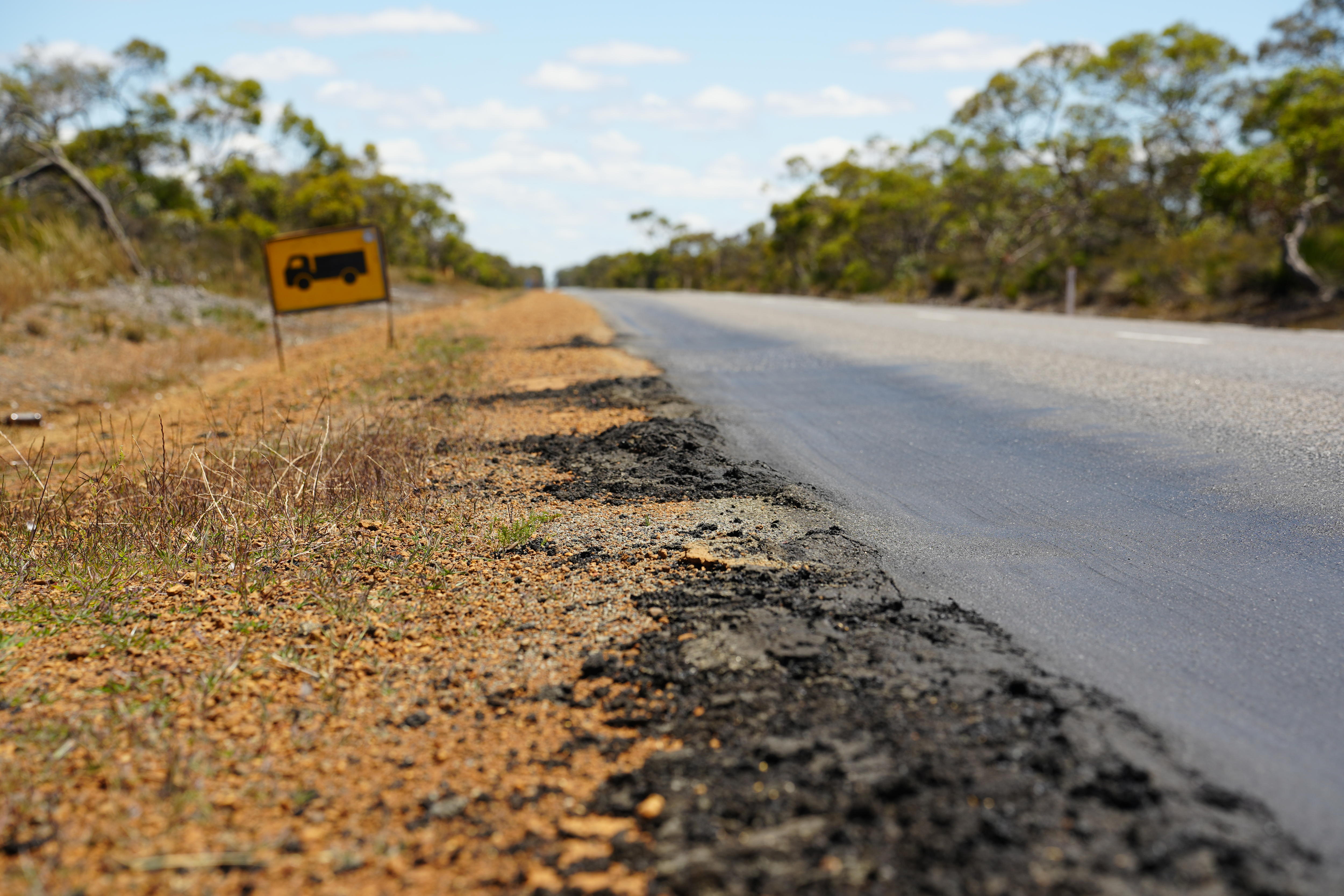 Close up of a road edge where the bitumen is crumbling and warped