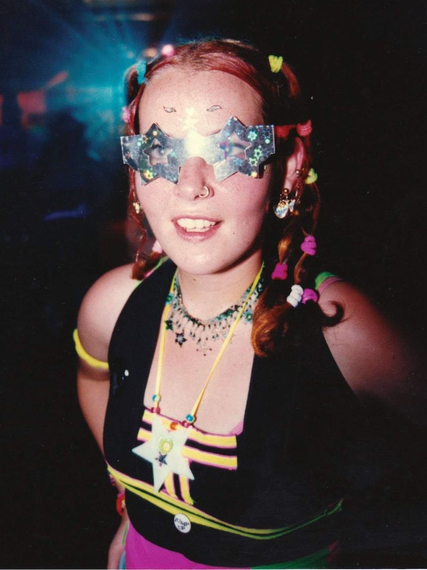 A young woman in a dark room wearing a sparkly star-shaped visor