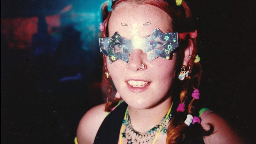 A young woman in a dark room wearing a sparkly star-shaped visor
