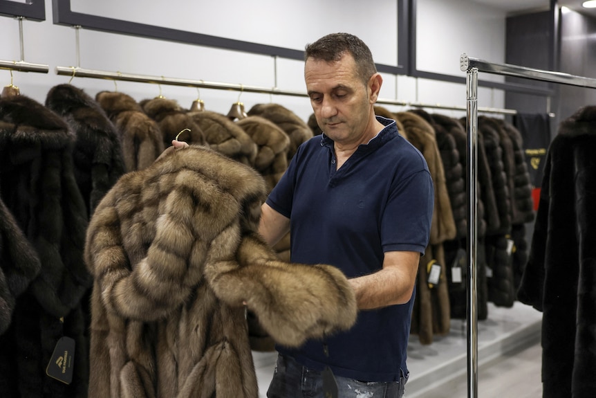 Antonis Disios holds a fur coat inside his shop,