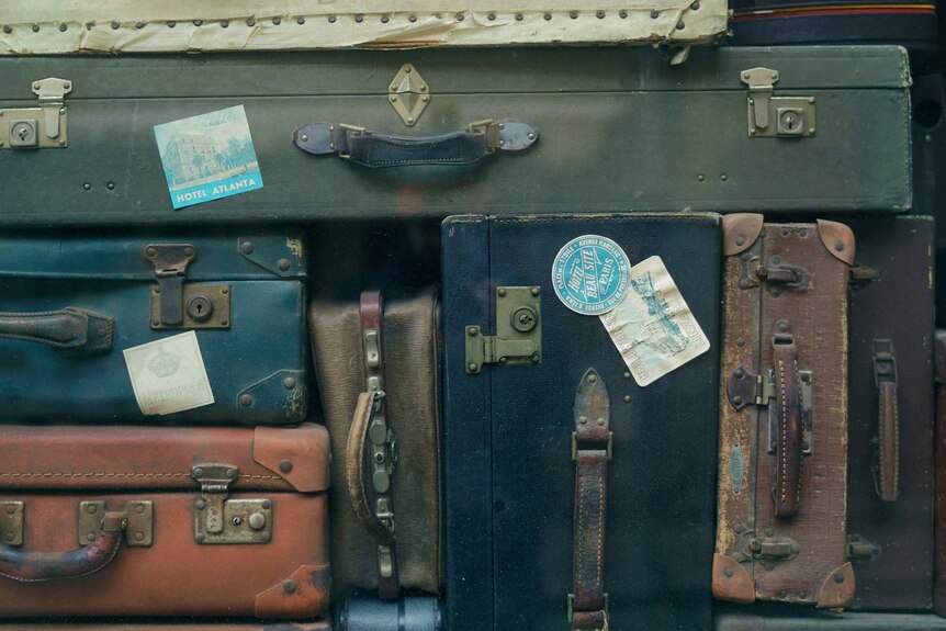 old suitcases with stickers from international travel destinations stacked up in a pattern