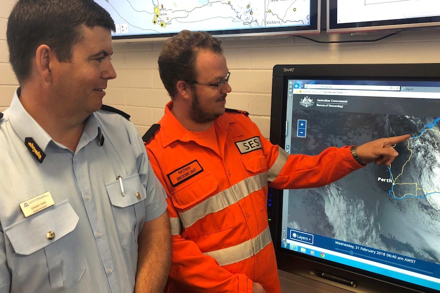 DFES Kimberley superintendent Grant Pipe and SES volunteer Nathan Donald stand looking at a satellite map on a screen.