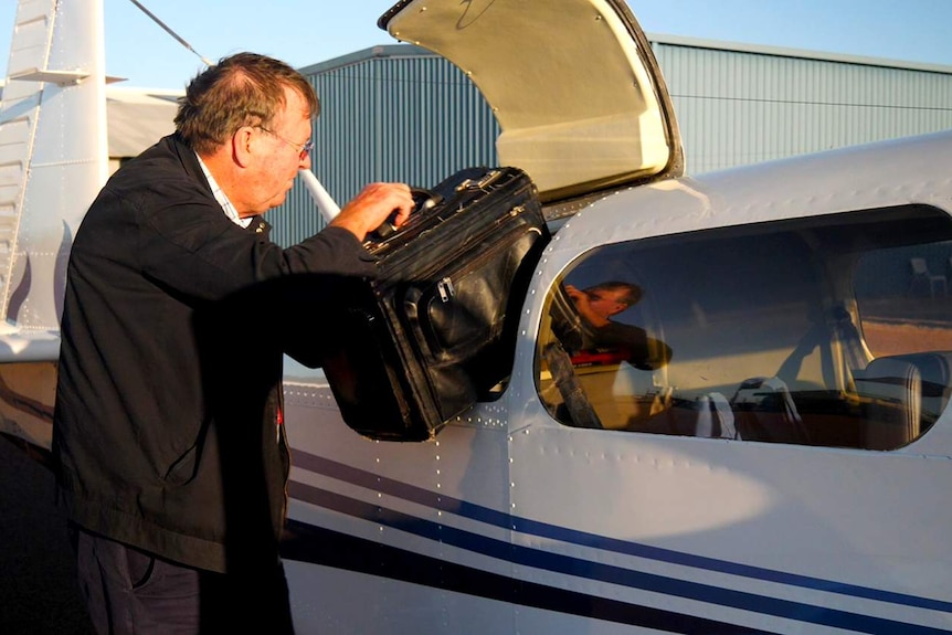 A man pulling suitcases out of a light plane