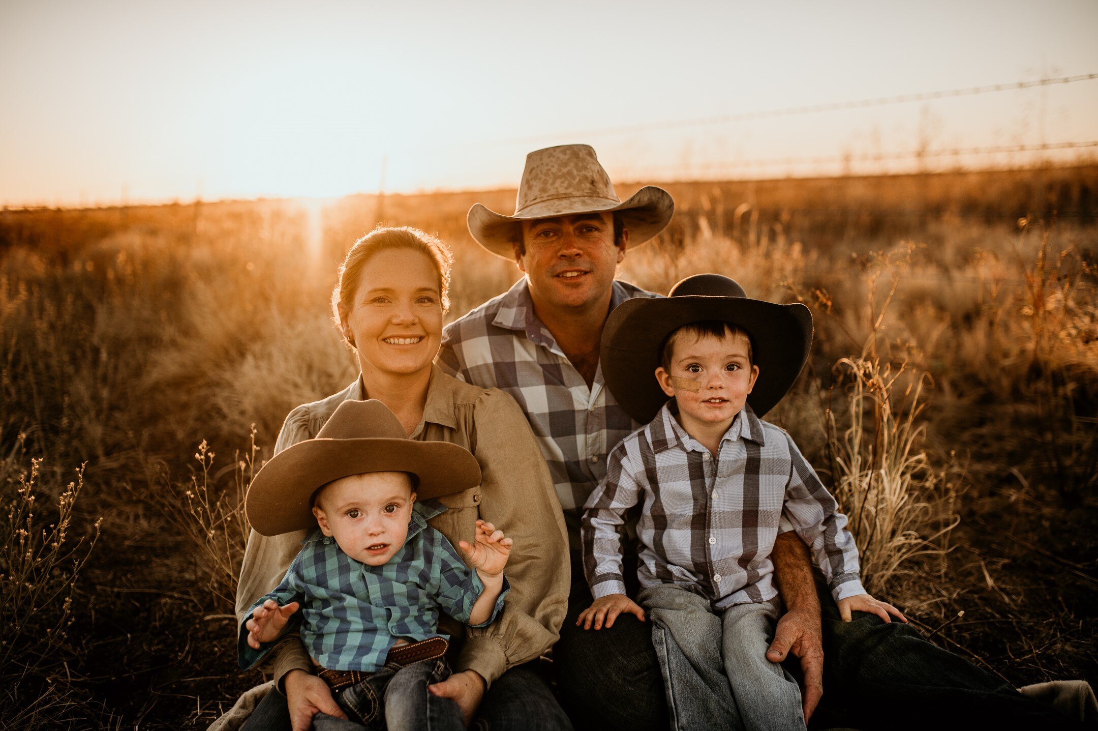Woman and partner in country clothes with their young boys in grassy field