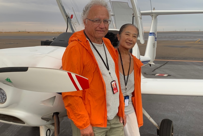 A man and woman stand next to a plane.