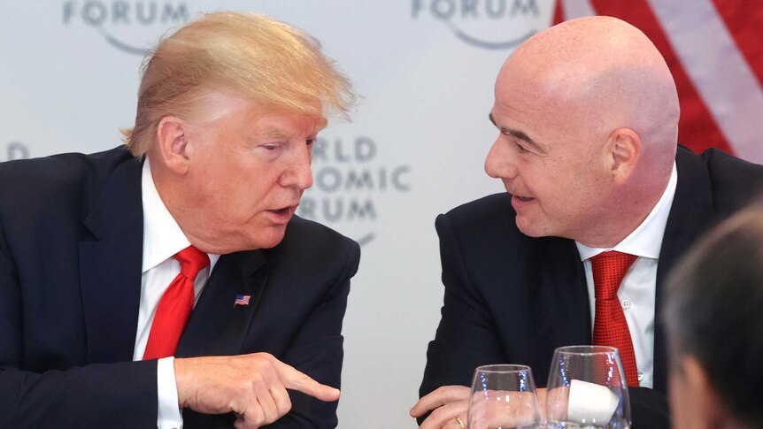 Donald Trump and Gianni Infantino lean towards eachother talking.