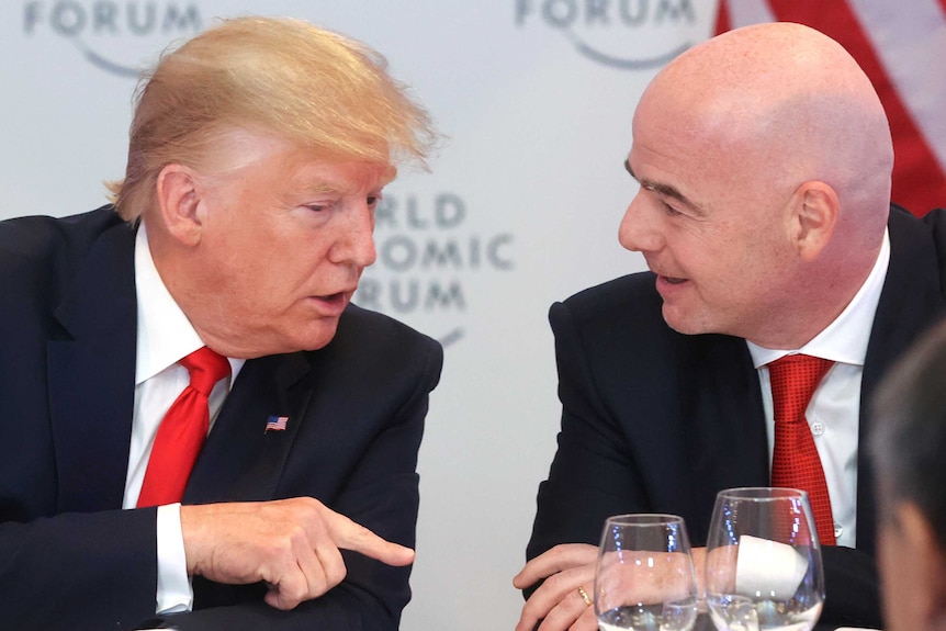 Donald Trump and Gianni Infantino lean towards eachother talking.