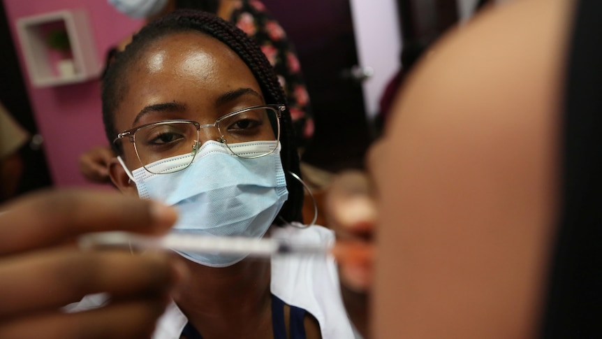 A masked healthcare worker administers a COVID-19 vaccine dose