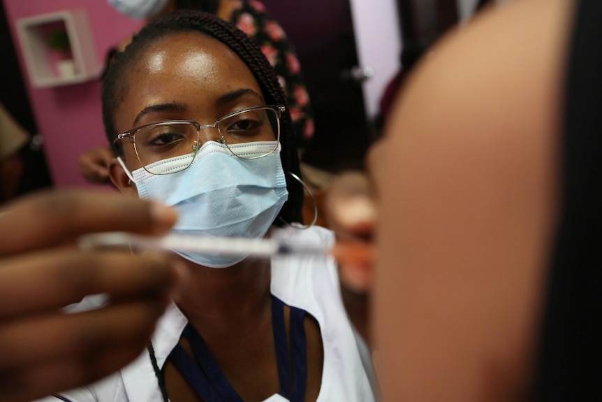 A masked healthcare worker administers a COVID-19 vaccine dose
