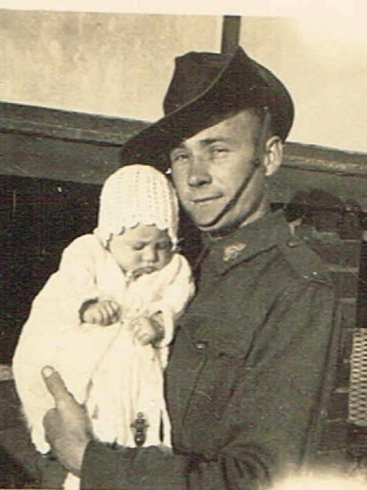 Archival photo of soldier Ronald Freeman, holding a baby in his arms.