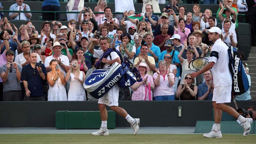 Australia's Lleyton Hewitt (L) leaves court alongside Andy Roddick after his loss at Wimbledon 2007.