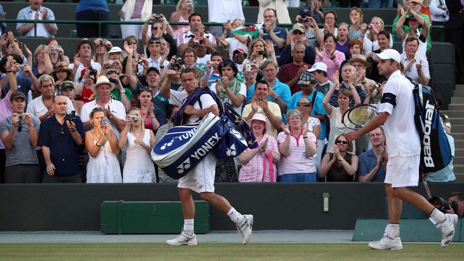 Australia's Lleyton Hewitt (L) leaves court alongside Andy Roddick after his loss at Wimbledon 2007.