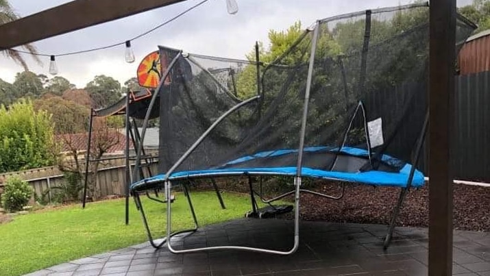 A trampoline in a back yard.