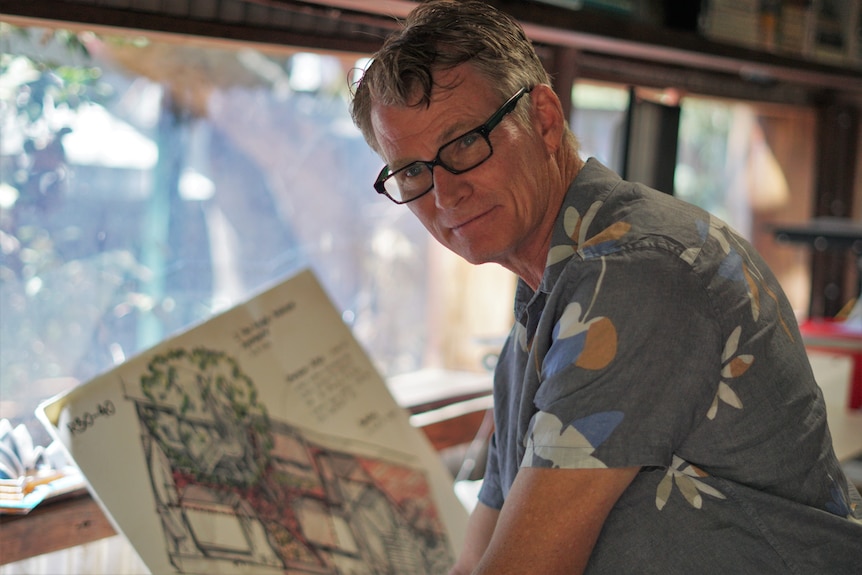 A man leaning over a desk with a sketch in front of him