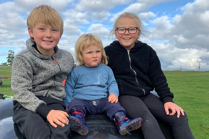 Three children sit atop a silage bale in northern Tasmania.