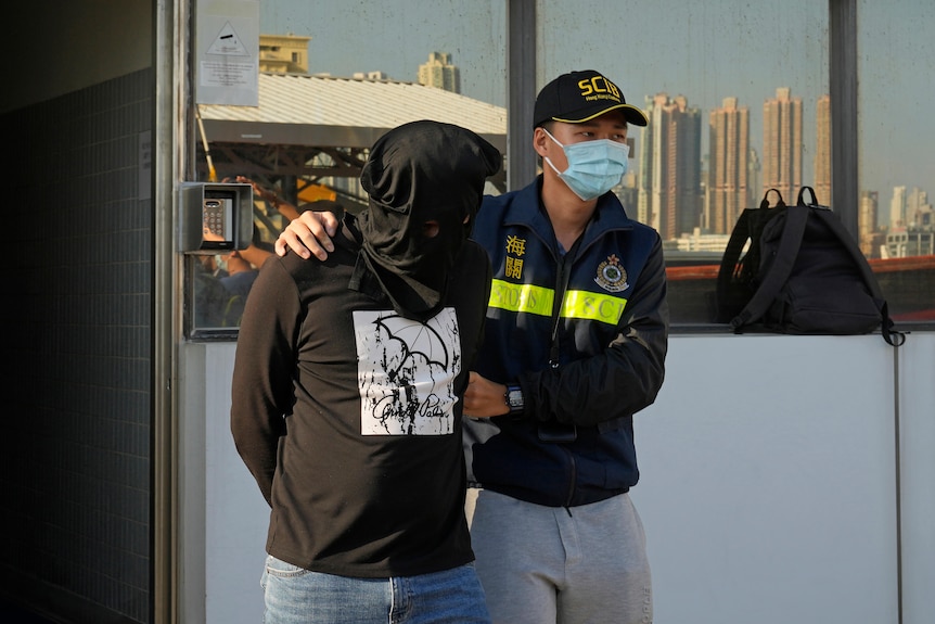 A suspected smuggler is escorted by officers from the Hong Kong Customs