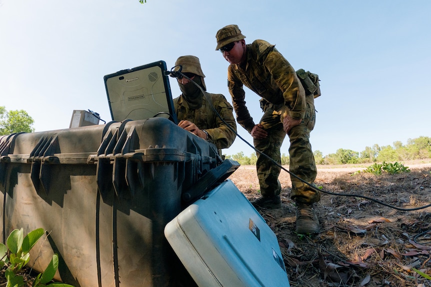two army personnel operating an aircraft using a laptop