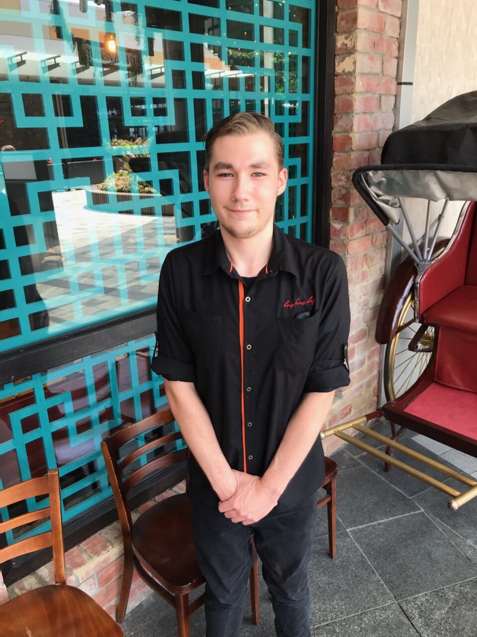 an image of young man in a black hospital uniform in front of brick building