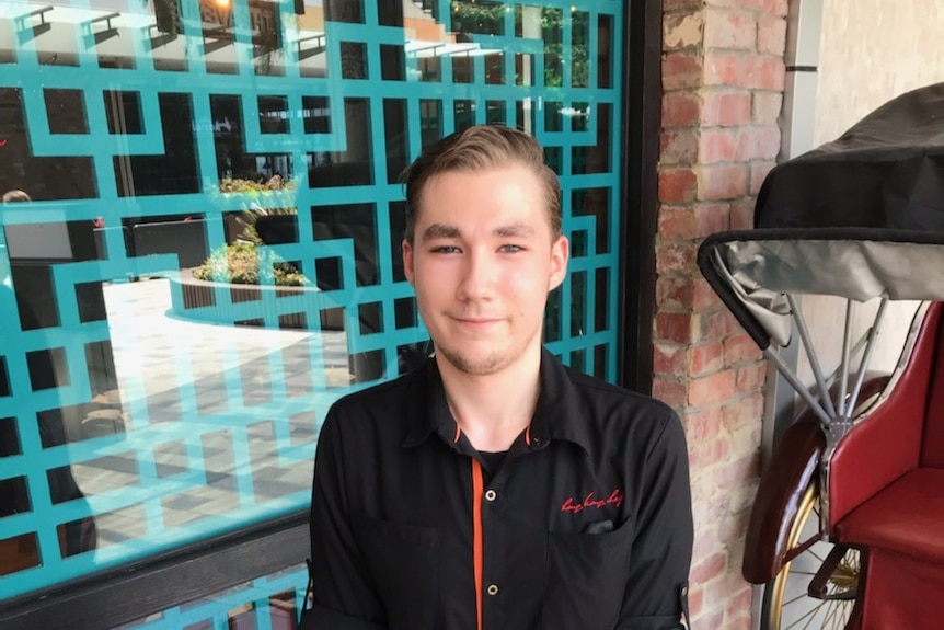 an image of young man in a black hospital uniform in front of brick building