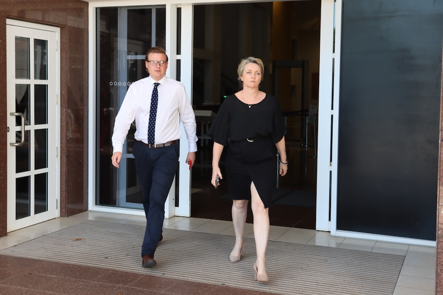 Een professioneel ogende man en een vrouw lopen de ingang van het NT Supreme Court uit.