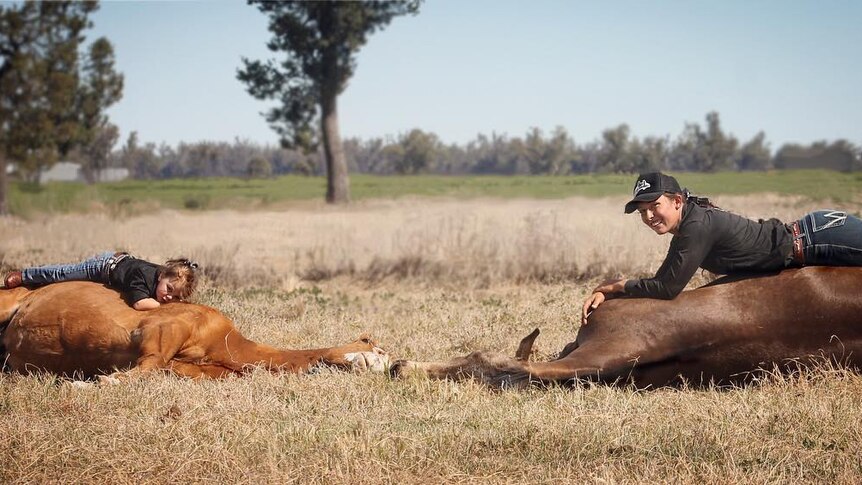 A woman and a young girl lying on some horses