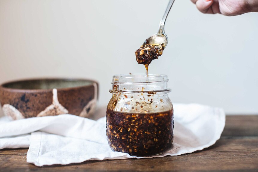 A teaspoon of homemade chilli oil, from our recipe for congee, being lifted out of a jar.