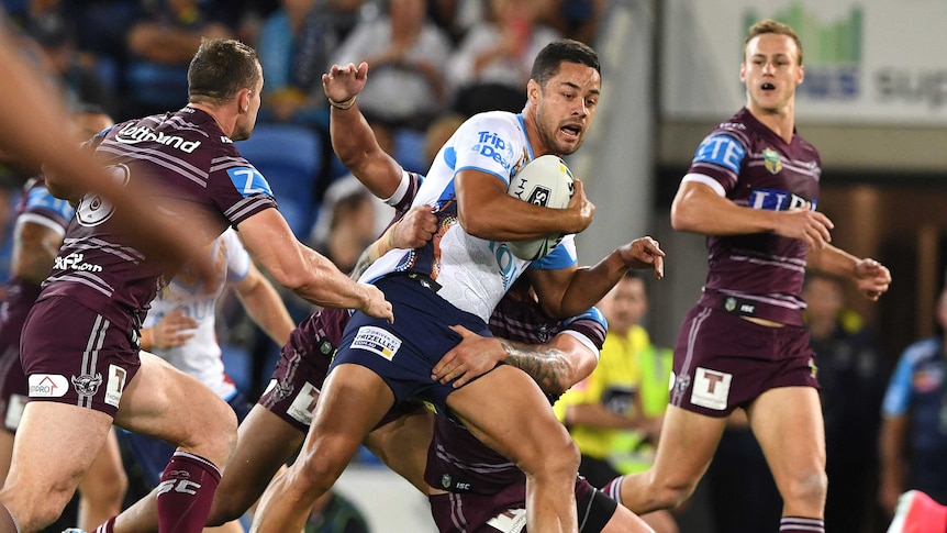 Jarryd Hayne carries the ball as he is tackled by Manly players