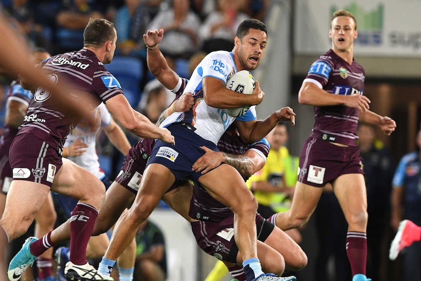 Jarryd Hayne carries the ball as he is tackled by Manly players