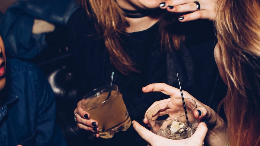 Friends holding drinks and having a laugh at a bar