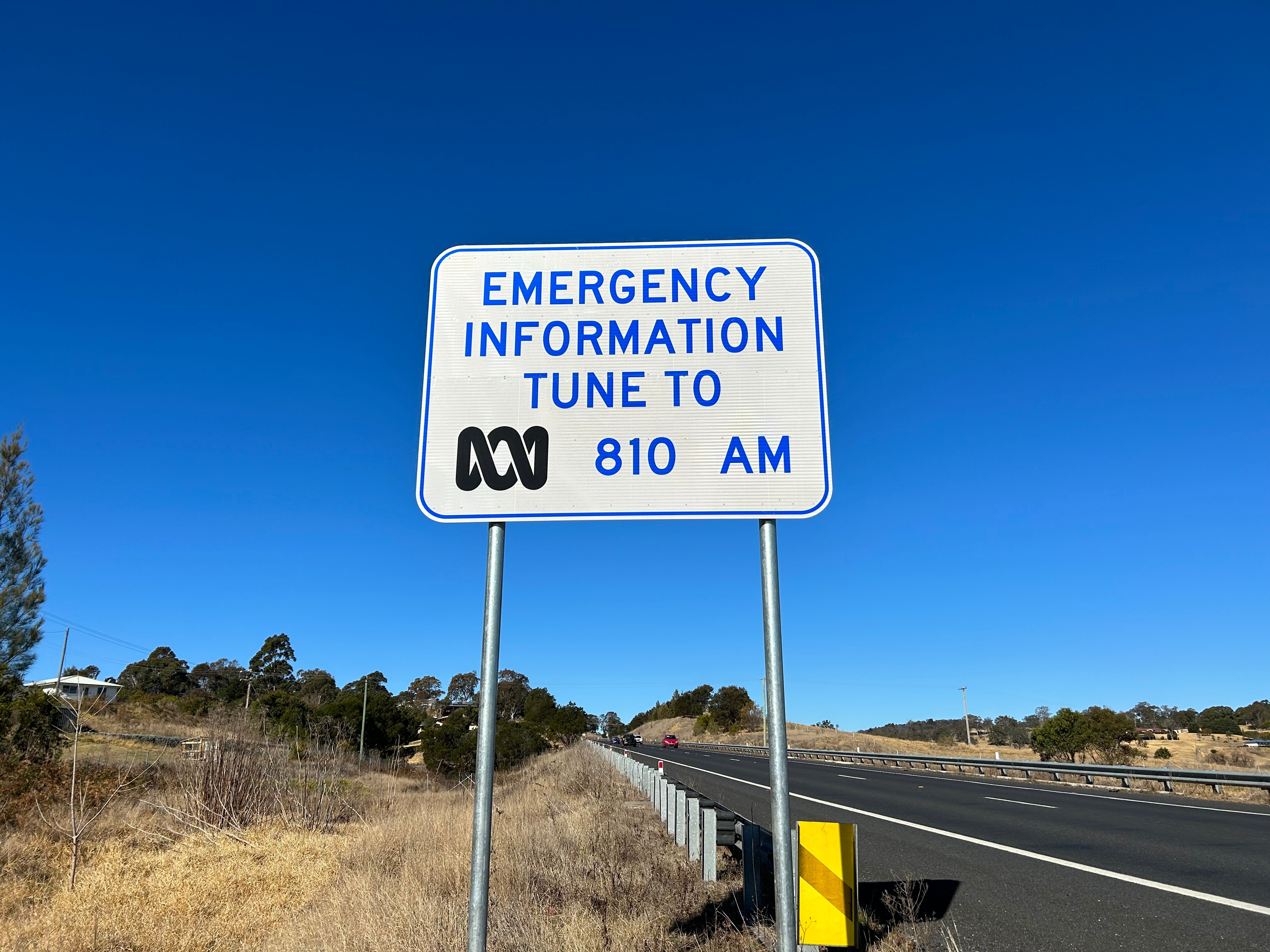 A roadside sign displaying the radio frequency for local ABC Emergency broadcasts in the Bega area. 
