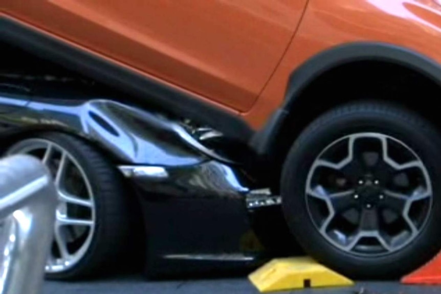 The front of a sportscar underneath another car.