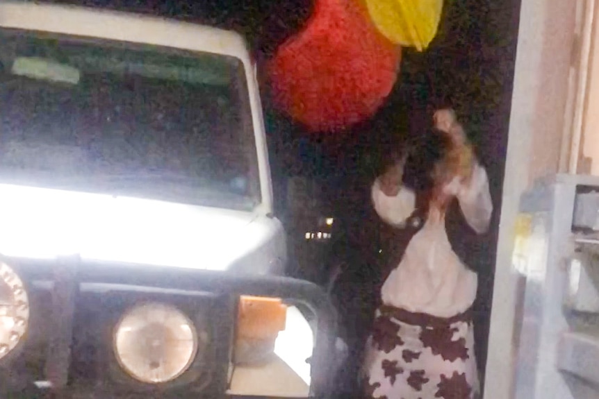 A still from a video showing Karen Ridge trying to pull down an Aboriginal flag.