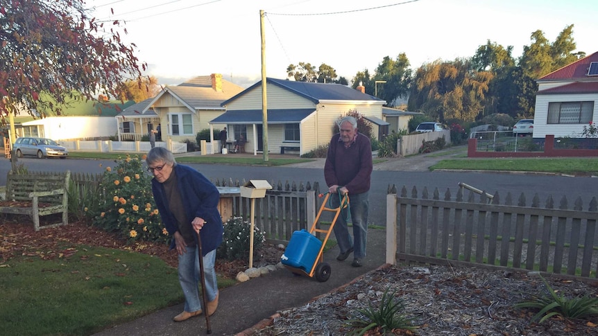 An elderly Tasmanian couple cart water to their house in Tasmania's north-east.