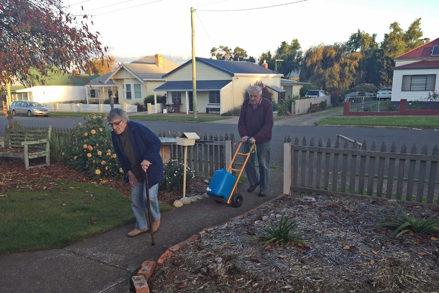 An elderly Tasmanian couple cart water to their house in Tasmania's north-east.