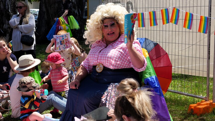 Dean Arcuri, a drag artist also known as Frock Hudson, reads a book to a group outside Shepparton Library
