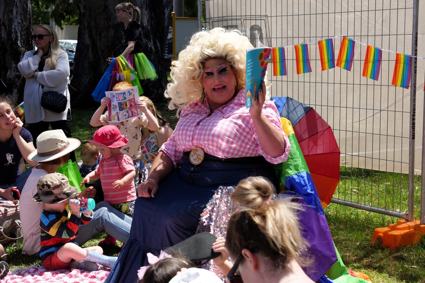 A drag queen reads a book to a group of children.
