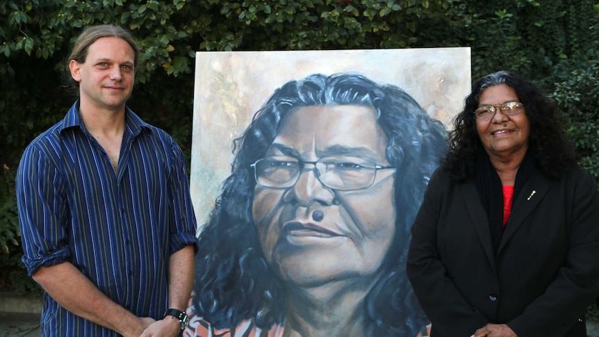 Artist Chris Bailey with his Archibald Prize entry portrait of Josie Farrar and the subject herself, with foliage in background.