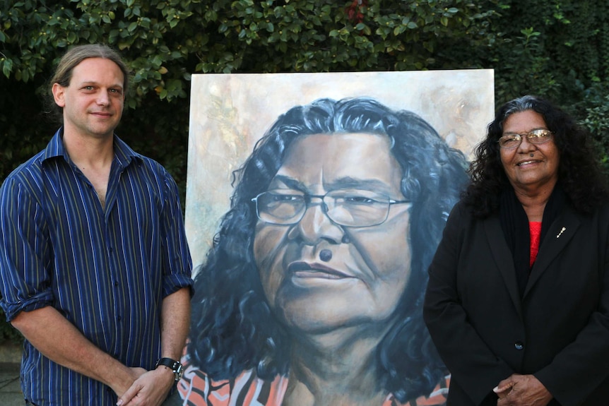 Artist Chris Bailey with his Archibald Prize entry portrait of Josie Farrar and the subject herself, with foliage in background.