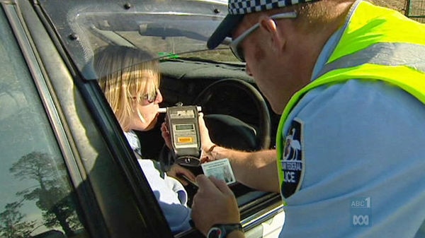 Policeman conducts a roadside breath test on driver.